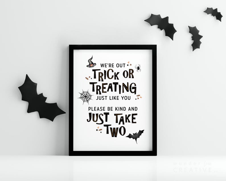 May include: A framed Halloween sign with black text that reads "We're out trick or treating just like you, please be kind and just take two." Black bat cutouts decorate the white wall.