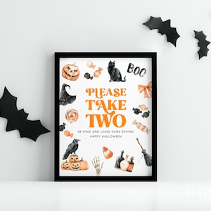 May include: A framed Halloween-themed print with a black border. The print features watercolor illustrations of a pumpkin, black cat, candy, and a witch's hat. Text reads "PLEASE TAKE TWO" and "BE KIND AND LEAVE SOME BEHIND HAPPY HALLOWEEN."