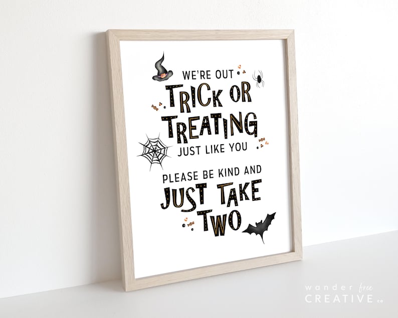 May include: A framed Halloween-themed print with the text "WE'RE OUT TRICK OR TREATING JUST LIKE YOU PLEASE BE KIND AND JUST TAKE TWO." The print features a witch's hat, spider, spiderweb, and bat illustrations in black and gold.
