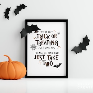 May include: A framed Halloween sign with the text "We're out trick or treating just like you, please be kind and just take two." An orange pumpkin and black bat decorations are also present.