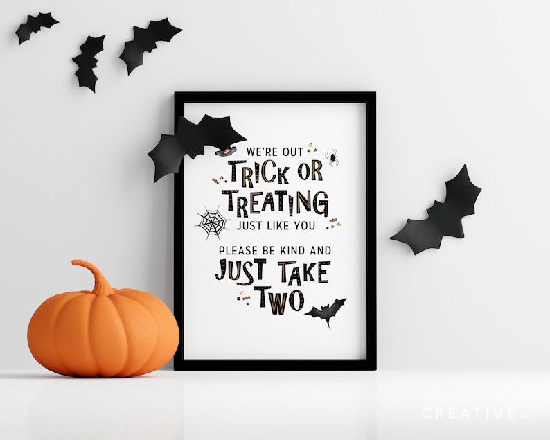 May include: A framed Halloween sign with the text "We're out trick or treating just like you, please be kind and just take two." An orange pumpkin and black bat decorations are also present.