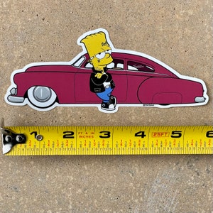 Może przedstawiać: Żółta postać z kreskówki w niebieskiej koszuli i czarnej skórzanej kurtce opierająca się o czerwony samochód vintage. Samochód ma białe koła i białe obramowania wokół okien. Postać ma tatuaż na ramieniu z napisem "15".