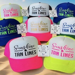Puede incluir: Una colecci&oacute;n de ocho gorras de camionero en varios colores, incluyendo amarillo ne&oacute;n, negro, azul, rosa y verde. Cada gorra presenta un panel frontal blanco con el texto Sunshine & TAN LINES impreso en diferentes colores y una etiqueta de marca.