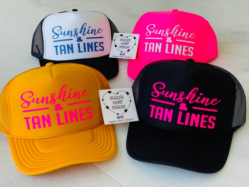 Puede incluir: Cuatro gorras de camionero en negro, blanco, rosa ne&oacute;n y amarillo, cada una con el texto Sunshine & TAN LINES en colores contrastantes. Se ven dos peque&ntilde;as etiquetas cuadradas blancas con el texto RUGGED HEART DESIGNS e iconos sociales.