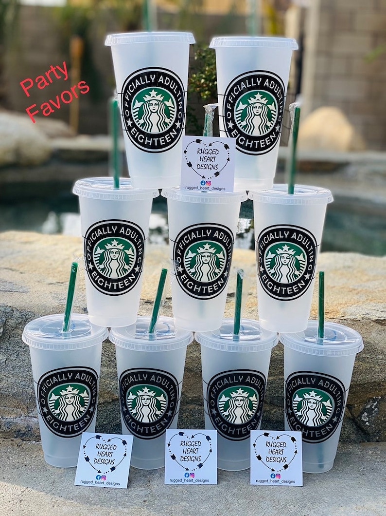 May include: Eight clear plastic cups with black and white designs that say "Officially Adulting Eighteen" with a Starbucks logo.  The cups are arranged in a circle with a sticker on each cup that says "Rugged Heart Designs".