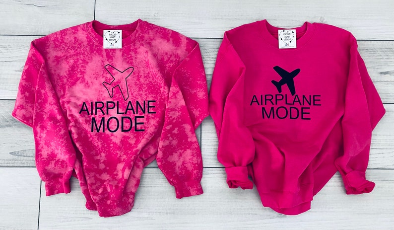 May include: Two pink sweatshirts with the text "AIRPLANE MODE" and a black airplane graphic. One sweatshirt has a tie-dye pattern.