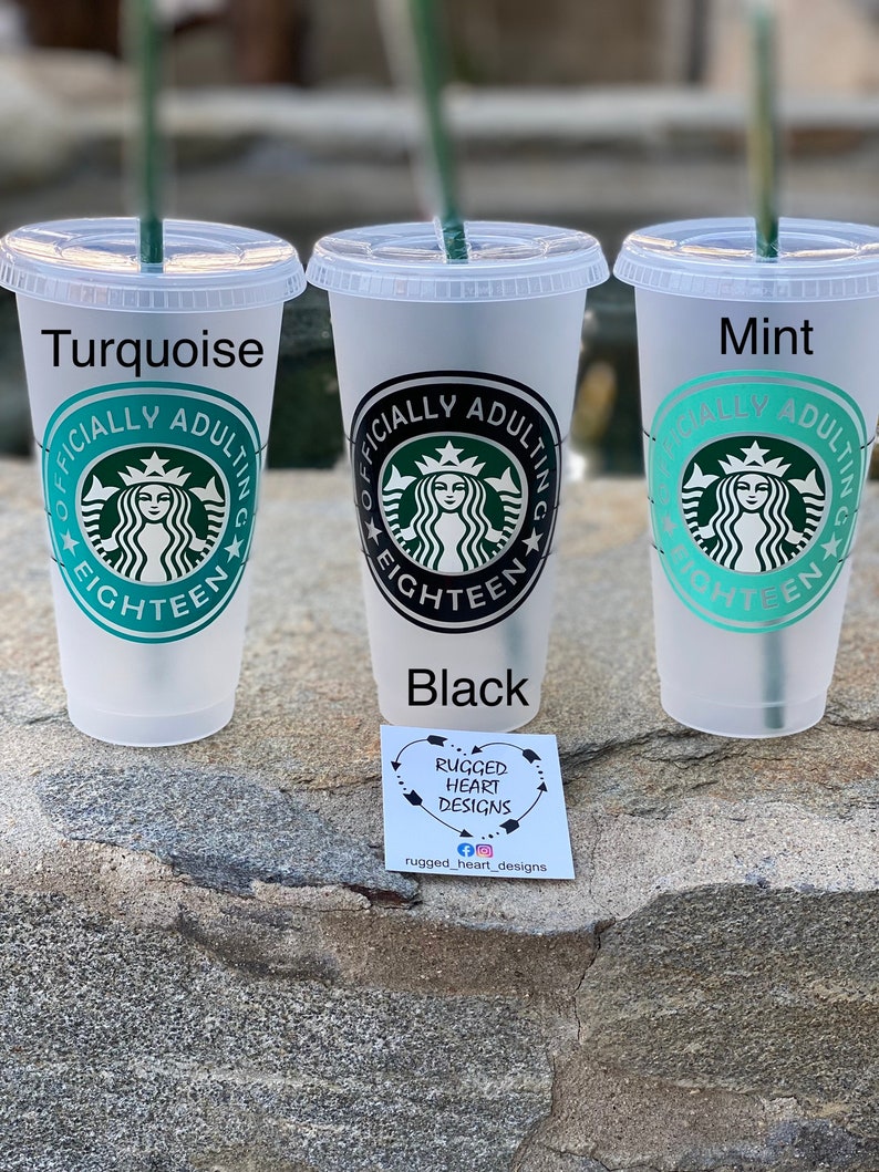May include: Three reusable plastic cups with lids and straws. The cups are turquoise, black, and mint green. Each cup has a black and white design with the text "Officially Adulting Eighteen" and a stylized image of a mermaid.