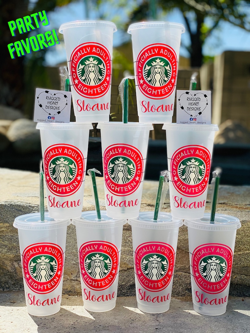 May include: Eight clear plastic cups with lids and straws. Each cup has a pink and white design that says "Officially Adulting" with a Starbucks logo and the name "Sloane" printed on the bottom.