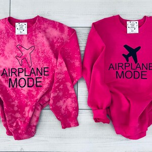 May include: Two pink sweatshirts with the text "Airplane Mode" and a small airplane graphic. One sweatshirt has a tie-dye effect.