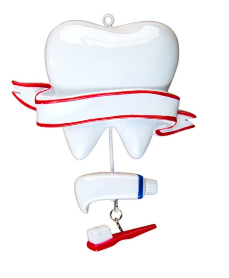 May include: A white tooth ornament with a red ribbon and a white banner. The tooth is hanging from a string with a white tube of toothpaste and a red toothbrush hanging below.