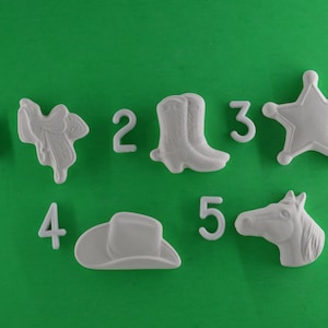 May include: White ceramic cookie cutters shaped like a cowboy boot, a cowboy hat, a horse head, a star, a saddle, and the numbers 1 through 5.