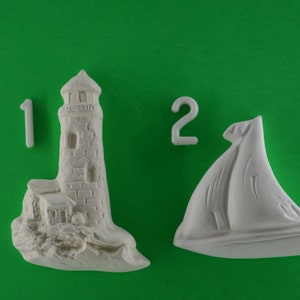 May include: Two white ceramic figurines, one of a lighthouse and the other of a sailboat. The lighthouse is numbered "1" and the sailboat is numbered "2".
