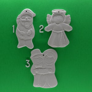 May include: Three white ceramic ornaments, ready to be painted. The ornaments are shaped like Santa Claus, an angel, and a couple. The ornaments are numbered 1, 2, and 3.