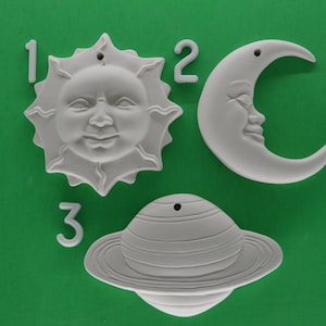 May include: Three white ceramic ornaments, a sun, a crescent moon, and a planet with rings. The ornaments are numbered 1, 2, and 3.