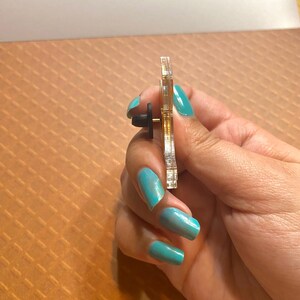 May include: A gold and clear iridescent enamel pin with a butterfly design. The pin has a black rubber clutch back.