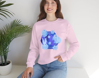 May include: A pink sweatshirt with a blue and white graphic of four bunnies in a hexagonal shape with flowers. The bunnies are stylized and have a cartoonish appearance.