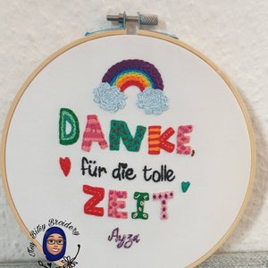 May include: Embroidered hoop art with the German phrase "Danke f&uuml;r die tolle Zeit" (Thank you for the great time). The design features a rainbow, clouds, hearts, and colourful text on white fabric, framed in a wooden hoop.