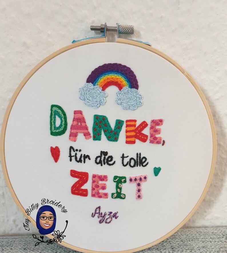 May include: Embroidered hoop art with the German phrase "Danke f&uuml;r die tolle Zeit" (Thank you for the great time). The design features a rainbow, clouds, hearts, and colourful text on white fabric, framed in a wooden hoop.
