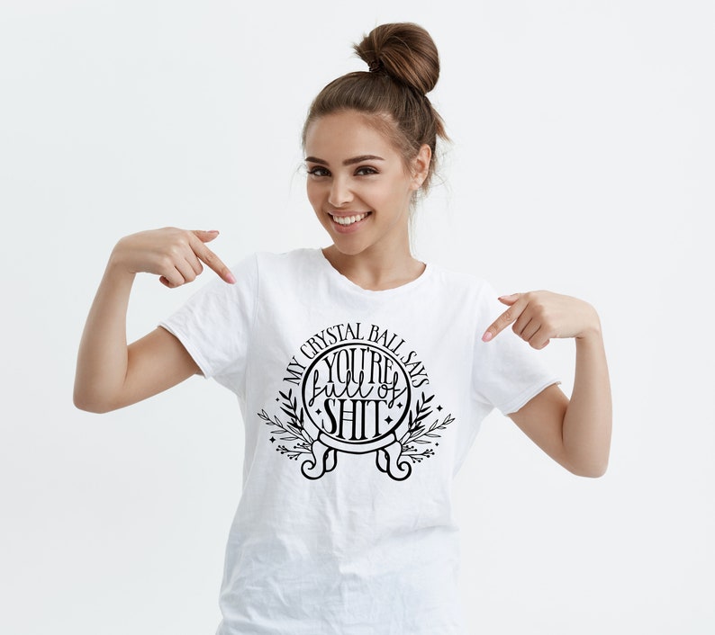 May include: White t-shirt with a black graphic design that says "My Crystal Ball Says You're Full of Shit" with a circle around the text and a floral design.