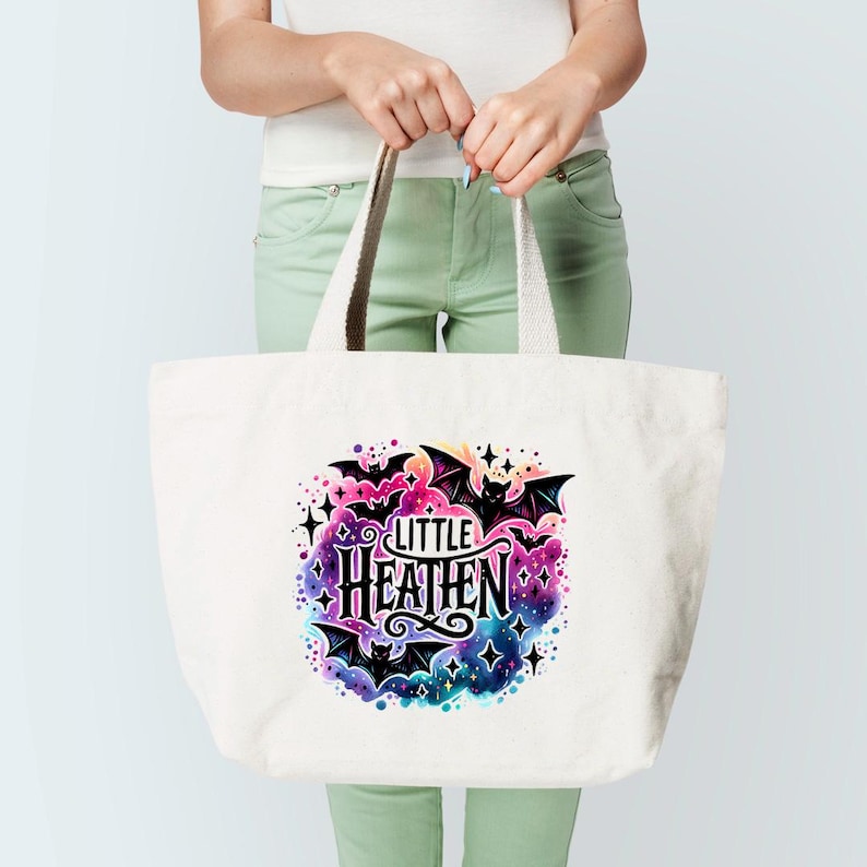 May include: A white tote bag with a colorful design featuring bats, stars, and the text "Little Heathen".