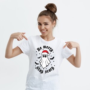 May include: White t-shirt with a ghost wearing a Santa hat and the text "Be merry. Stay scary."