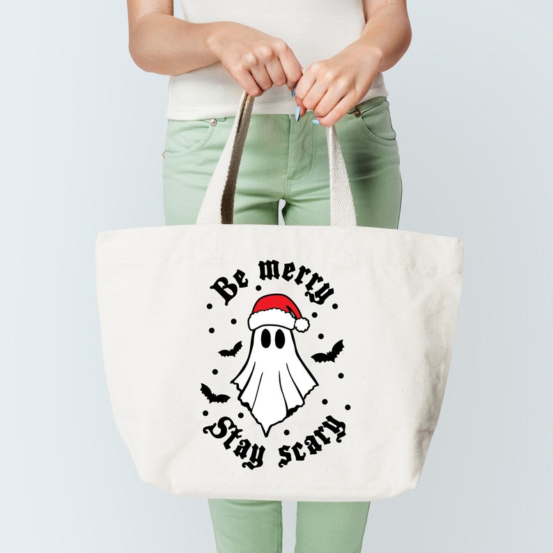 May include: White tote bag with a ghost wearing a Santa hat and the text "Be merry. Stay scary."
