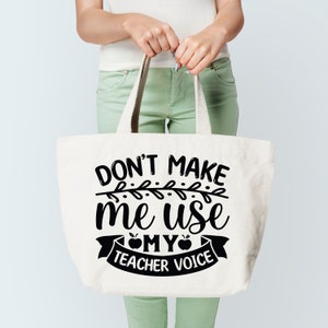 Puede incluir: Una bolsa de lona blanca con texto negro que dice "Don't make me use my teacher voice" con una manzana negra y un dise&ntilde;o de vid negra.