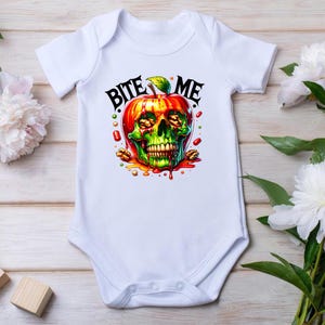 May include: White baby onesie featuring a red apple with a green skull inside. The apple has a green stem and leaves. The text "Bite Me" is above the apple.
