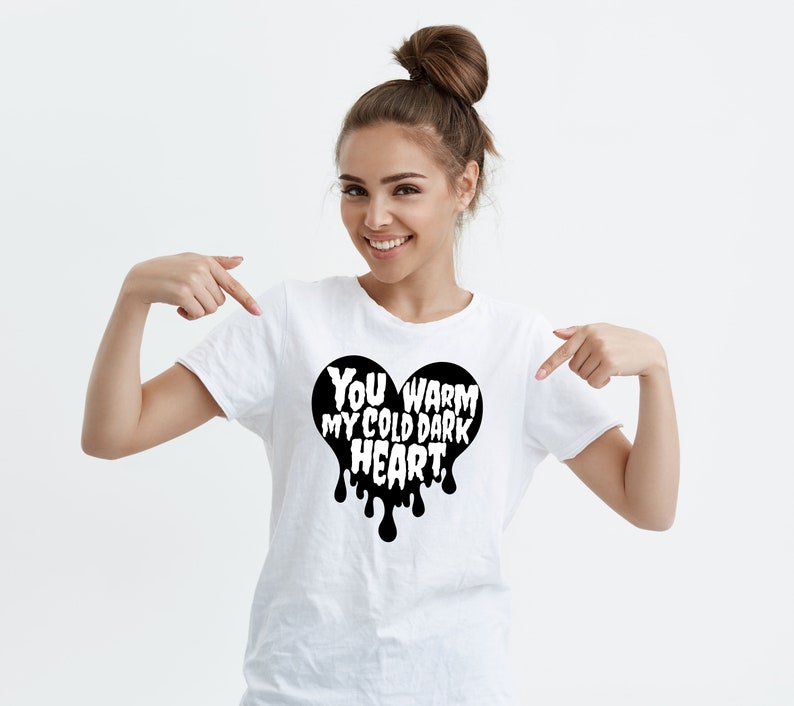 May include: White t-shirt with a black heart graphic that says "You warm my cold dark heart".