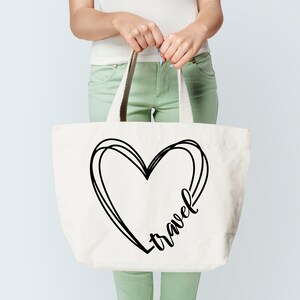 K&ouml;nnte beinhalten: Eine wei&szlig;e Canvas-Tragetasche mit schwarzen Henkeln. Die Tasche hat eine schwarz-wei&szlig;e Grafik eines Herzens mit dem Wort "Reise" darin.