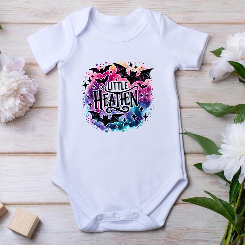 May include: White baby onesie with a colorful watercolor design featuring bats and the text "Little Heathen".