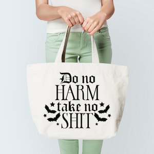 May include: White canvas tote bag with black text that reads "Do no HARM take no SHIT" with bat silhouettes and stars around the text.