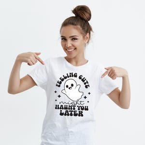May include: White t-shirt with a black and white graphic of a ghost with the text "Feeling Cute Might Haunt You Later".