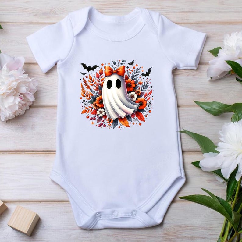 Może przedstawiać: Białe body dla niemowląt z motywem Halloween. Grafika przedstawia kresk&oacute;wkowego ducha z czerwoną kokardą, otoczonego pomarańczowymi kwiatami, liśćmi i czarnymi nietoperzami. Body wykonane jest z miękkiego materiału i ma kr&oacute;tkie rękawy.