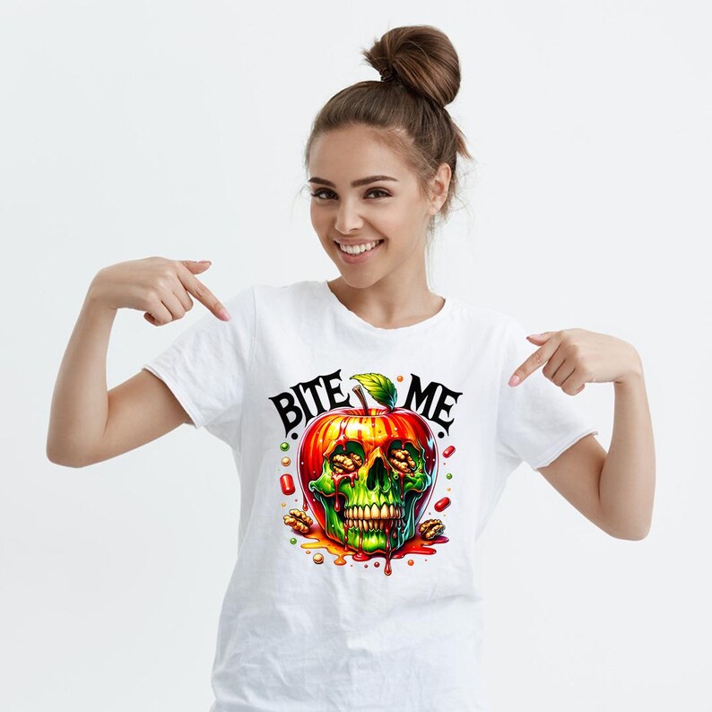 May include: White t-shirt featuring a red apple graphic. The apple is a skull with candy and nuts inside. The text "Bite Me" is above the apple.