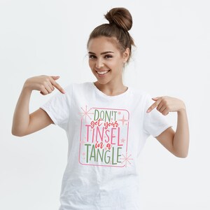 May include: White t-shirt with a pink and green graphic that says "Don't get your tinsel in a tangle".