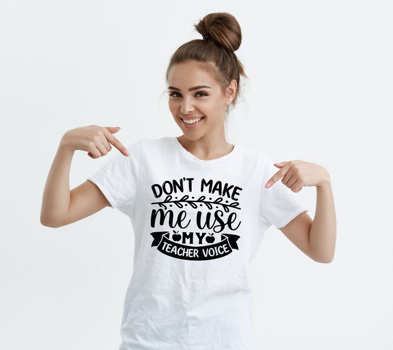 Puede incluir: Camiseta blanca con texto negro que dice "No me hagas usar mi voz de maestro" con un peque&ntilde;o gr&aacute;fico de manzana y un dise&ntilde;o de vid.
