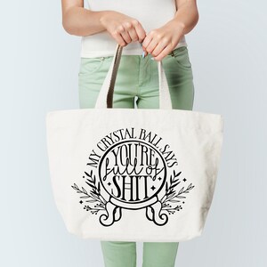 May include: White tote bag with a black graphic of a crystal ball that says "My Crystal Ball Says You're Full of Shit".