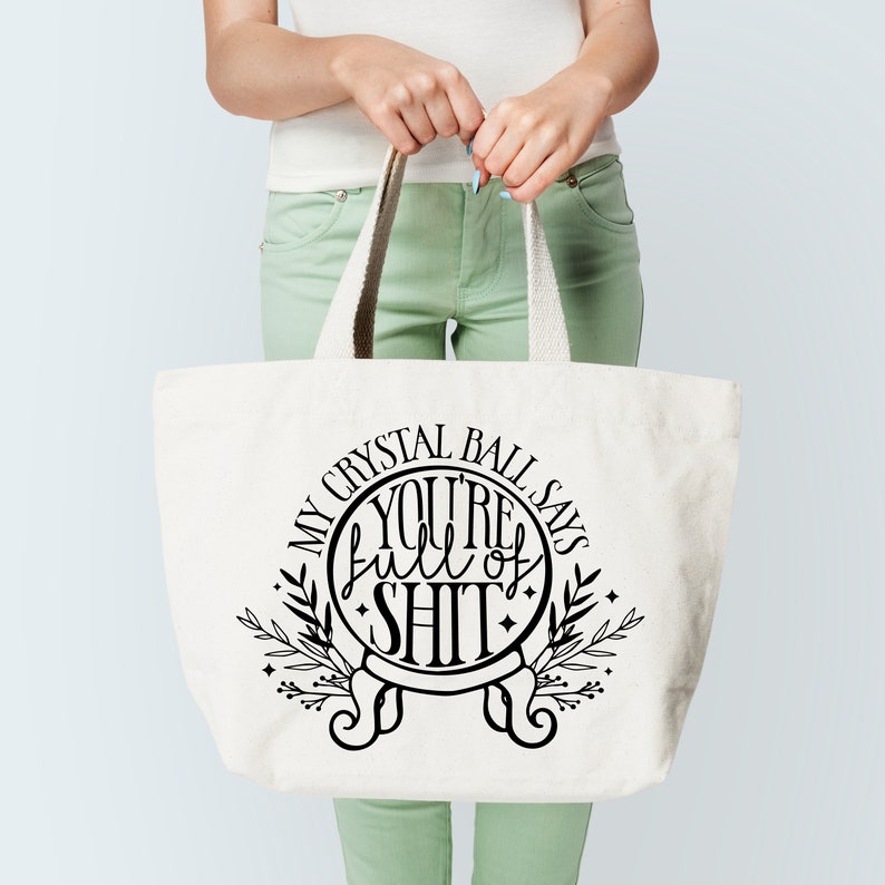 May include: White tote bag with a black graphic of a crystal ball that says "My Crystal Ball Says You're Full of Shit".