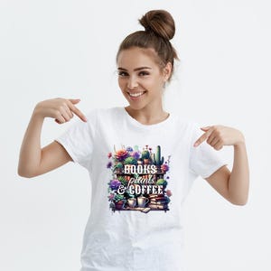 May include: White t-shirt featuring a colorful graphic of a bookshelf with plants, books, and coffee cups. The text on the graphic reads "Books, Plants, & Coffee". The design includes various succulents, flowers, and coffee mugs.