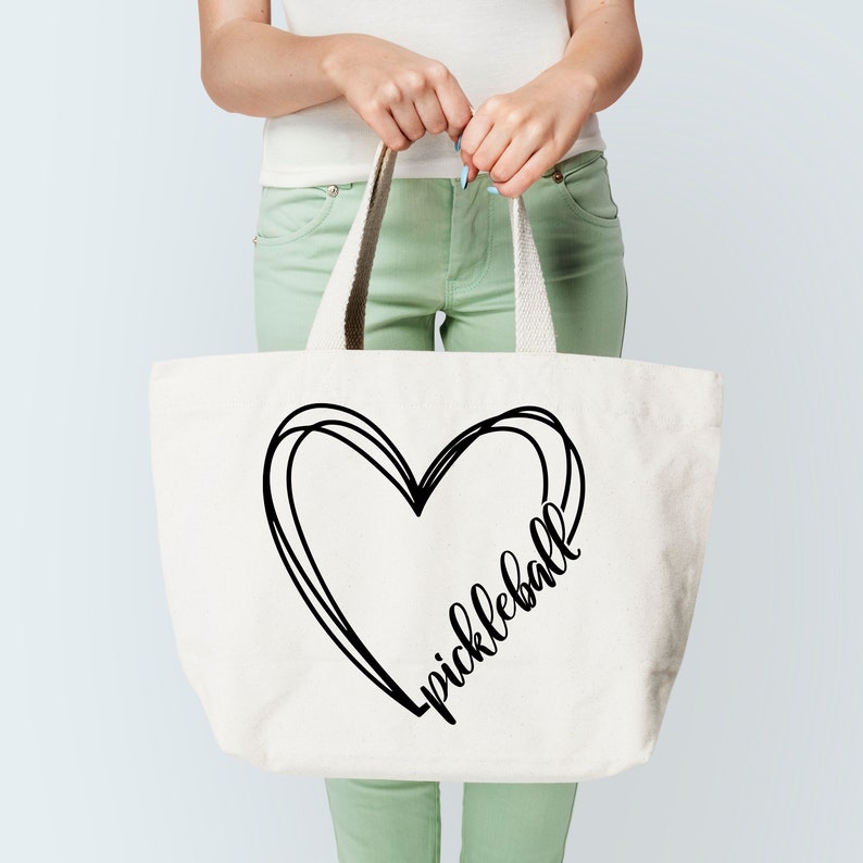 May include: A white canvas tote bag with black handles and a black heart design that says "pickleball" inside the heart.