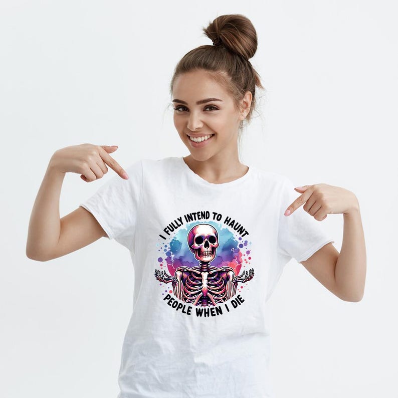 K&ouml;nnte beinhalten: Wei&szlig;es T-Shirt mit einem farbenfrohen Skelett-Grafik und dem Text "I FULLY INTEND TO HAUNT PEOPLE WHEN I DIE". Das Design zeigt einen rosa Sch&auml;del und einen Aquarell-Effekt, passend f&uuml;r Halloween.