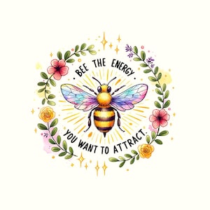 Op de afbeelding: Een aquarel-illustratie van een bij met regenboogvleugels, omringd door een krans van bloemen en bladeren. De tekst "Bee the energy you want to attract." is in een cirkel rond de bij geschreven.