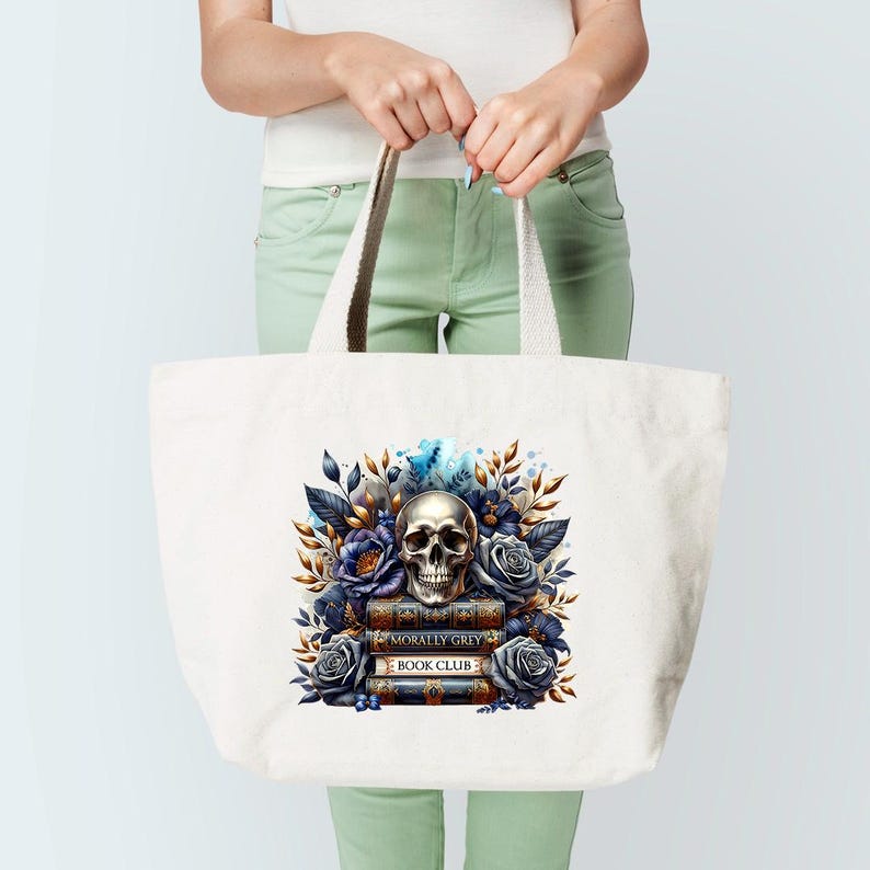 May include: A white tote bag with a skull and floral design. The skull is surrounded by blue and purple flowers and leaves. The text "Morally Grey Book Club" is printed on the books below the skull.