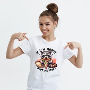 May include: White t-shirt with a graphic of a raccoon eating pizza and the text "If I'm Moody Give Me Foody".