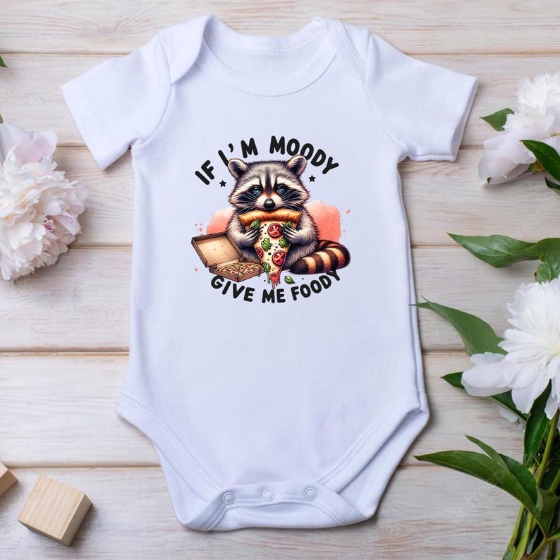 May include: White baby onesie with a graphic of a raccoon eating a pizza slice. The text on the onesie reads "If I'm Moody Give Me Fooddy".