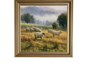 Op de afbeelding: Een ingelijst landschapsschilderij met een kudde witte schapen die grazen in een goudkleurig grasveld. Op de achtergrond zijn glooiende heuvels te zien die deels worden bedekt door een zachte ochtendmist en verspreide bomen.