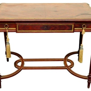 May include: A mahogany writing desk with a leather top, a single drawer, and brass accents. The desk has a decorative, curved, openwork base with a brass inlay.