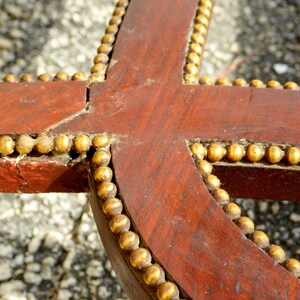 May include: Close-up of a wooden frame with a gold beaded trim. The frame is dark brown and the beads are a shiny gold color.