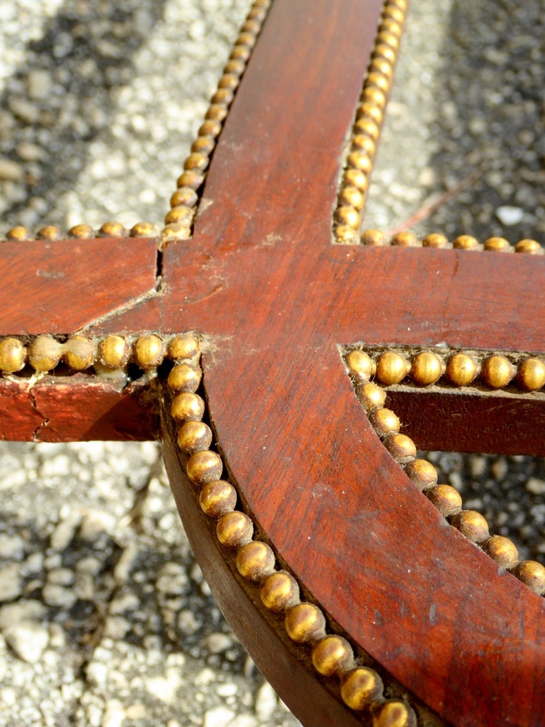 May include: Close-up of a wooden frame with a gold beaded trim. The frame is dark brown and the beads are a shiny gold color.
